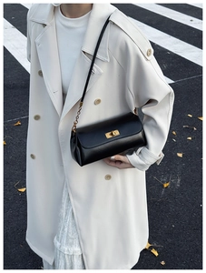 Detail of elegant black faux leather shoulder bag with golden metallic twist lock buckle