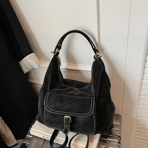 Detail of black faux leather backpack with white stitching and gold buckle on top