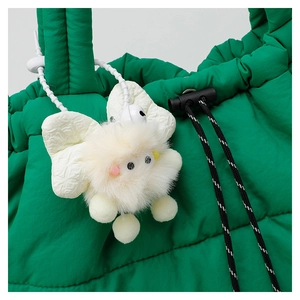Close-up of a cute yellow butterfly plush pendant hanging on a green quilted down bag