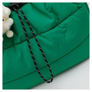 Detail of bright green quilted puffer tote bag with decorative cord and plush pendant