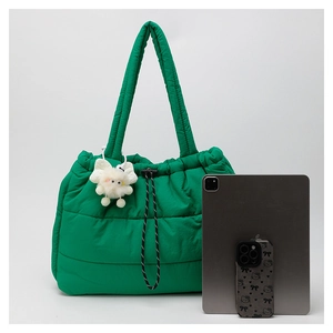 Detailed view of the green quilted tote bag with a plush charm and size comparison