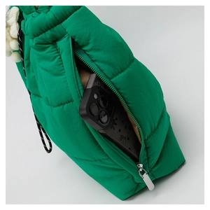 Detail view of green quilted down tote bag with side zipper pocket and plush charm