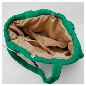 Interior view of green puffer tote bag showing zipper compartment and magnetic closure