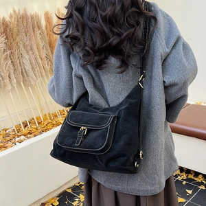 Detail of black vintage style shoulder bag with large front pocket and metal buckle clasp
