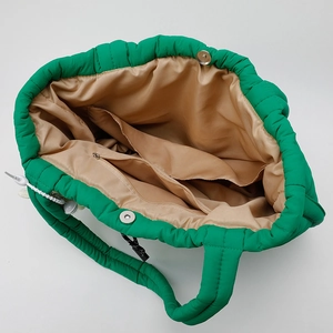 Green quilted puffer tote bag with spacious interior compartments and magnetic closure