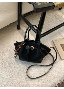 Dettaglio della borsa tote in pelle scamosciata nera con finiture e ciondolo in legno