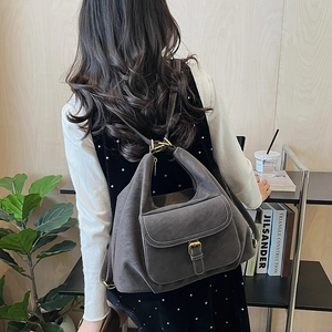 Close-up of dark grey leather backpack with vintage bronze hardware and adjustable straps
