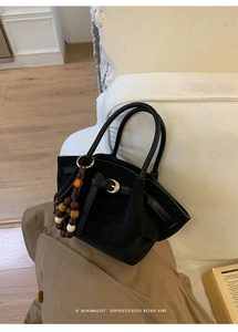 Dettaglio borsa tote in pelle scamosciata nera con fibbia dorata e ciondolo a perline