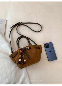 Dettaglio della borsa tote in pelle scamosciata marrone con pendente di perline