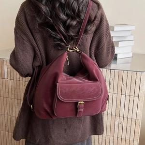 Detail of dark burgundy backpack with white contrast stitching and vintage gold buckle