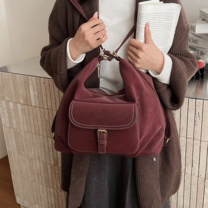 Detail of burgundy leather shoulder bag showing contrast stitching and front magnetic pocket