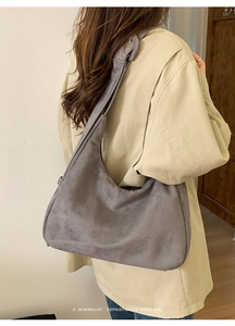 Détail d'un grand sac hobo en daim gris porté avec un manteau beige élégant