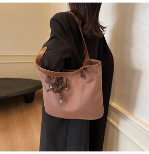 Detail of a large brown tote bag featuring a cute dachshund leather charm for daily use