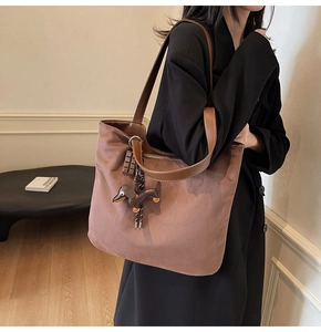 Detail of a large brown tote bag with leather strap and unique dachshund pendant accessory