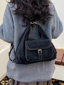 Classic black suede backpack with white stitching and gold buckle worn with a grey coat