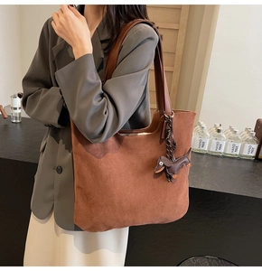 Close-up of brown suede tote bag featuring a cute puppy-shaped leather charm detail