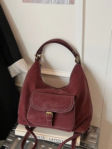 Vintage burgundy Hobo bag with white contrast stitching on a silver suitcase