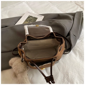 Detail view of the brown bucket backpack interior with drawstring and bear charm