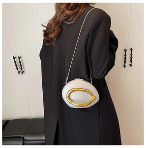 Detail van de witte kiezelvormige handtas met gouden metalen ring en ketting op model