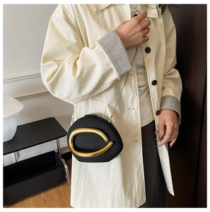 Detail van minimalistische zwarte crossbodytas met grote onregelmatige gouden metalen ring