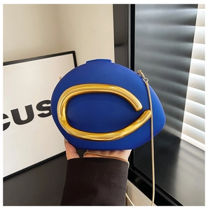 Detail van asymmetrische marineblauwe PU-clutch met grote gouden ring en metalen kettingriem
