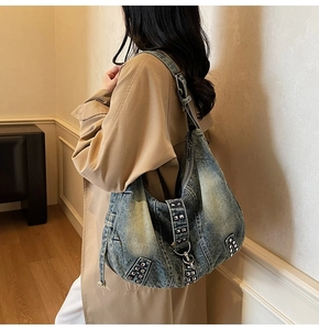 Detail einer Vintage-Denim-Hobo-Tasche mit Silbernieten an einem weiblichen Model