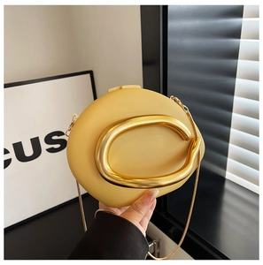 Detail van gele ovale avondtas met grote gouden metalen ringgreep en ketting