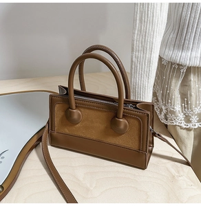 Detailed macro view of dark brown square bag with leather and suede splicing textures