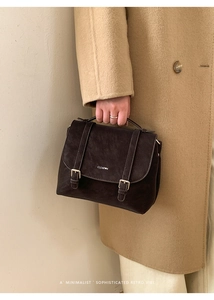 Dettaglio dello zaino vintage in pelle marrone con cinghie e manico superiore tenuto da una modella