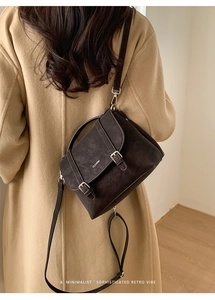 Modella che indossa una borsa retrò in pelle scamosciata marrone con un cappotto beige