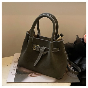Detail of dark olive suede handbag with white contrast stitching and gold buckle hardware