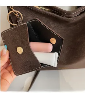 Détail du sac bandoulière en cuir grainé marron foncé avec une mini pochette aimantée