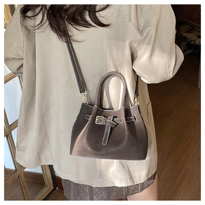Close-up of vintage brown bucket bag featuring white contrast stitching and buckle detail