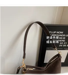 Détail du sac à bandoulière café avec surpiqûres blanches et ferrures dorées brillantes
