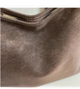 Gros plan du sac fourre-tout en cuir marron avec coutures contrastées et logo doré