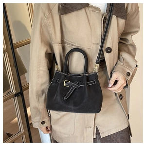 Detail of black leather handbag with white contrast stitching and gold buckle