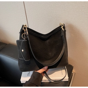 Gros plan du sac hobo en daim noir avec coutures blanches contrastées et détails dorés