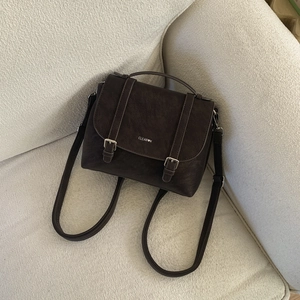 Dettaglio della borsa in similpelle marrone scuro con fibbie decorative e manico superiore