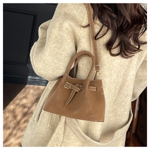 Close-up of brown leather bucket bag with elegant stitching and gold hardware detail