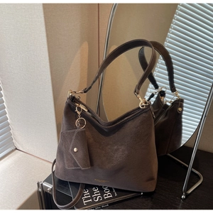 Détail du sac sous l'aisselle en daim café avec ferrures dorées et mini porte-monnaie