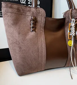 Dettaglio della borsa tote in pelle scamosciata marrone scuro con cuciture e ciondoli