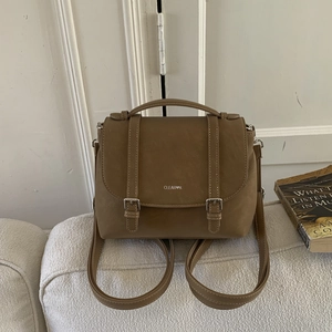 Dettaglio dello zaino in pelle PU marrone con doppie cinghie e logo del marchio