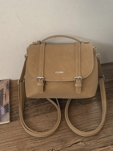 Zaino vintage in pelle PU color cammello con patta e manico su tavolo in legno