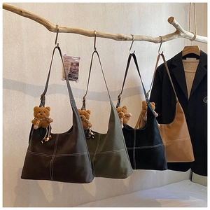 Detalle de cuatro bolsos de lona en tonos tierra colgados de ramas de madera natural