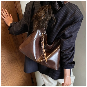 Détail du sac cabas vintage en cuir ciré marron foncé avec pendentif tressé élégant
