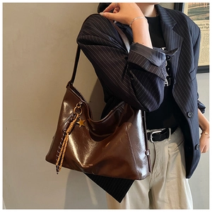 Détail du cabas en cuir marron foncé avec breloque étoile, franges et logo embossé