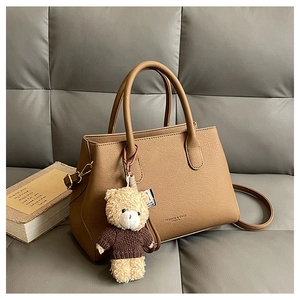 Dettaglio della borsa tote in pelle color cammello scuro con ciondolo a forma di orso