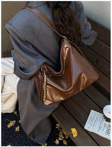Détail du sac cabas marron foncé en cuir huilé avec pendentif à pampilles tressées