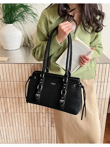 Dettaglio della borsa tote nera con fibbia argentata e logo di moda in rilievo