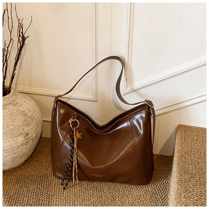 Détail du sac cabas vintage en cuir marron avec pendentif étoile dorée et fini huilé